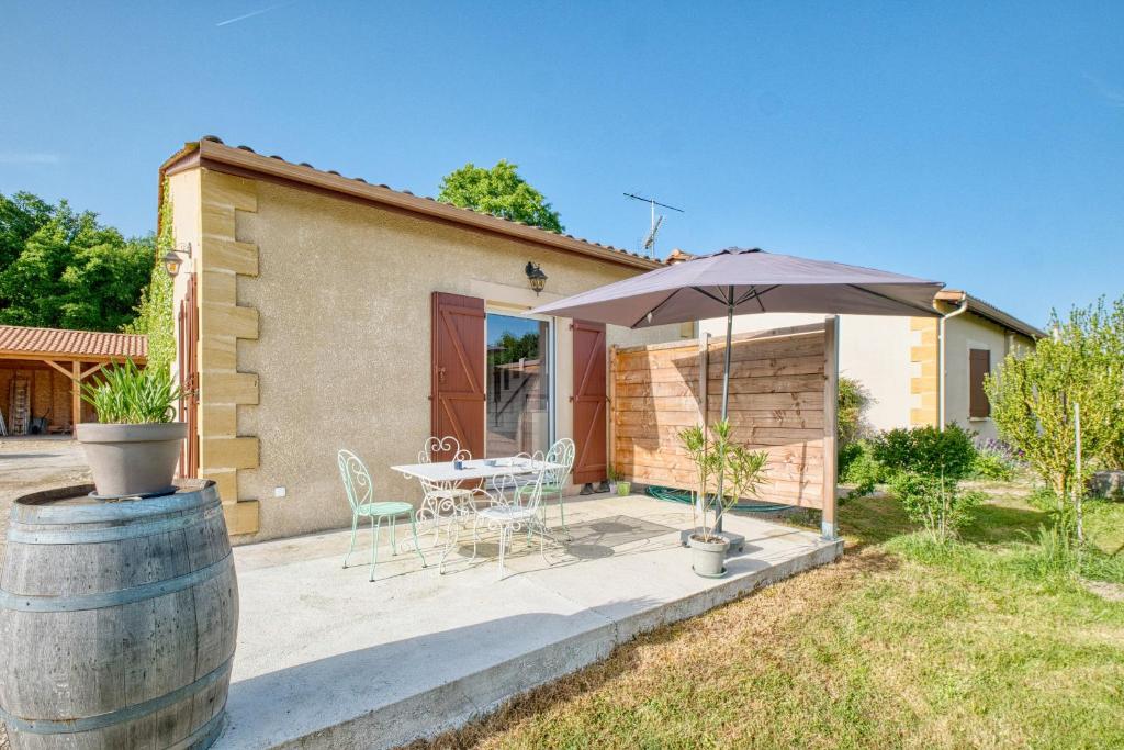 a patio with a table and an umbrella at Le Refuge des Vignes in Lamonzie-Saint-Martin