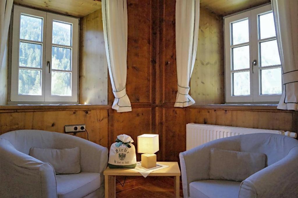 a living room with two chairs and two windows at Widum Obernberg Nikolaus Bergsuite in Obernberg am Brenner
