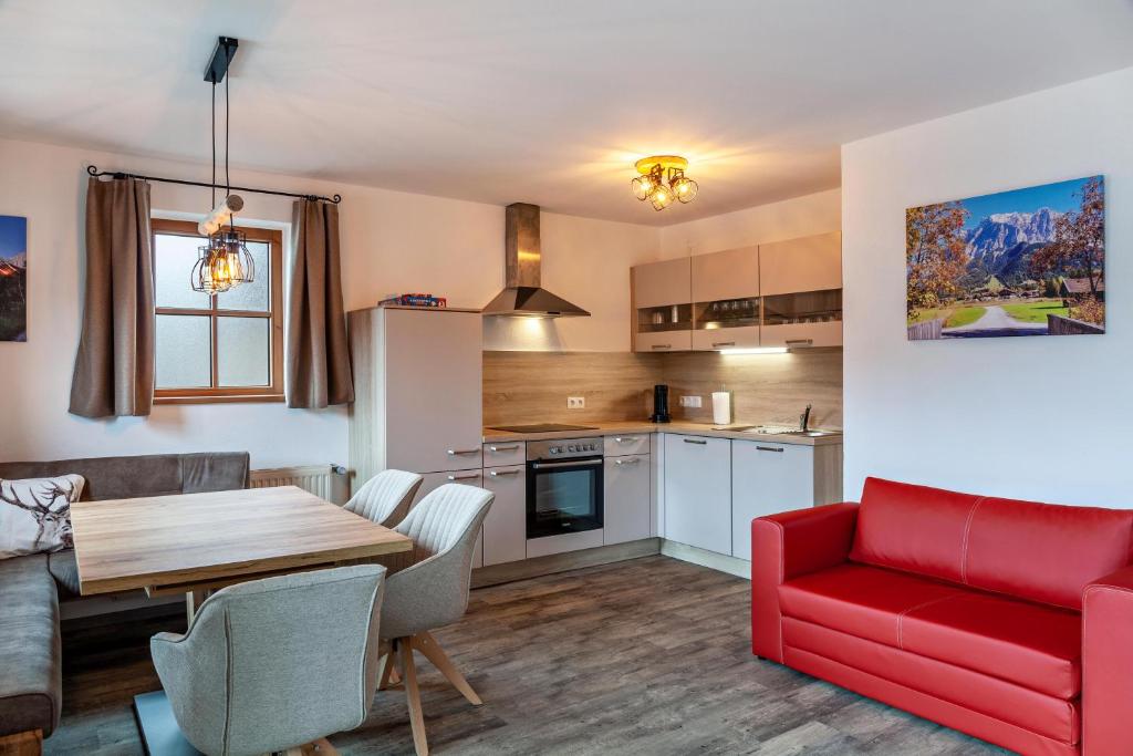 a kitchen and living room with a red couch and a table at Appartement by Blahut Vacation - og in Ehrwald