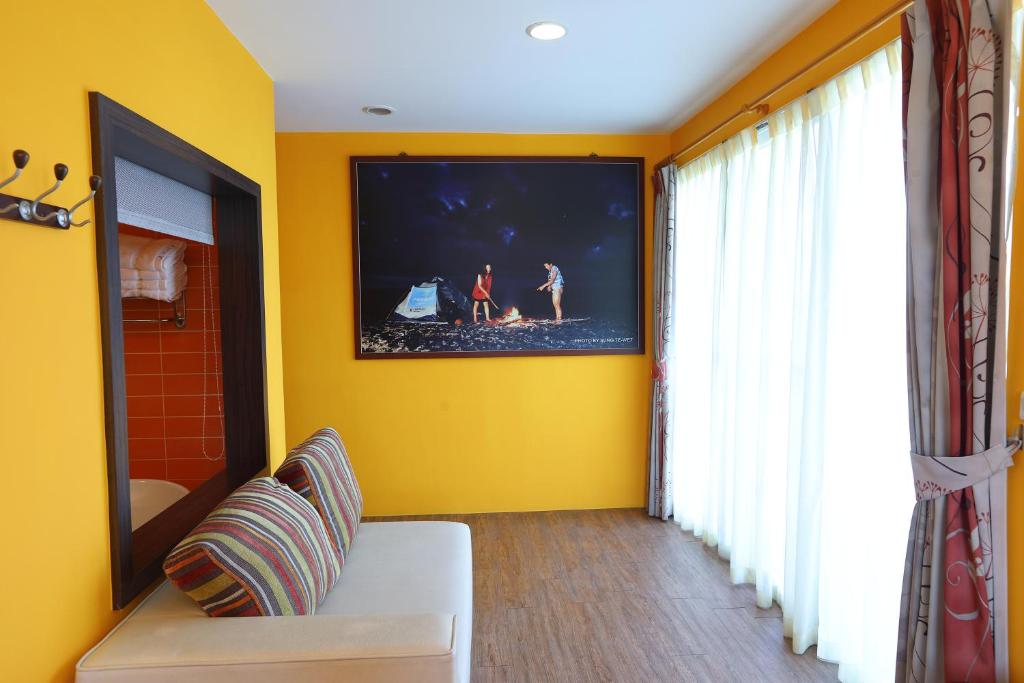 a yellow room with a couch and a tv on a wall at Hang Hai B&amp;B in Eluan