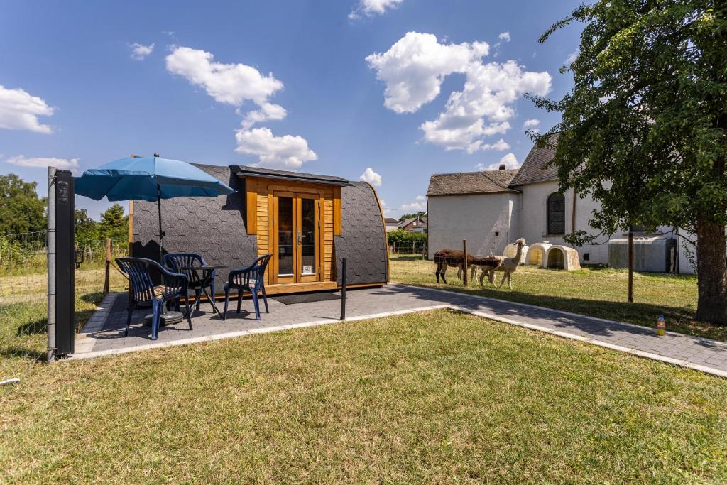 a small cabin with a table and chairs and an umbrella at Campingpod Auf Der Alpakawiese in Arnsberg
