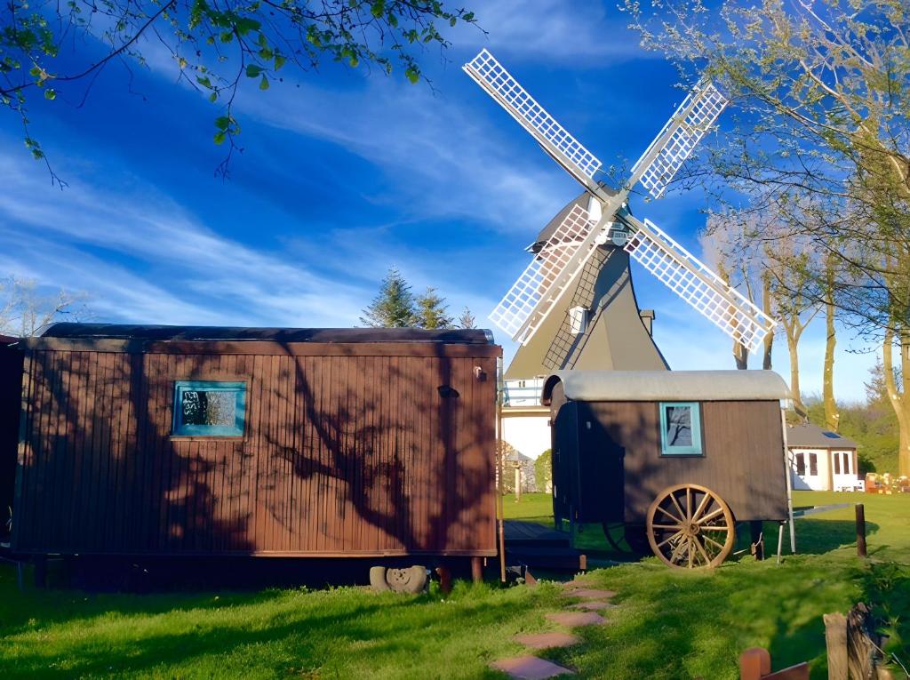 a large windmill with a shed next to a windmill at Traumwagen an der Mühle in Thalingburen