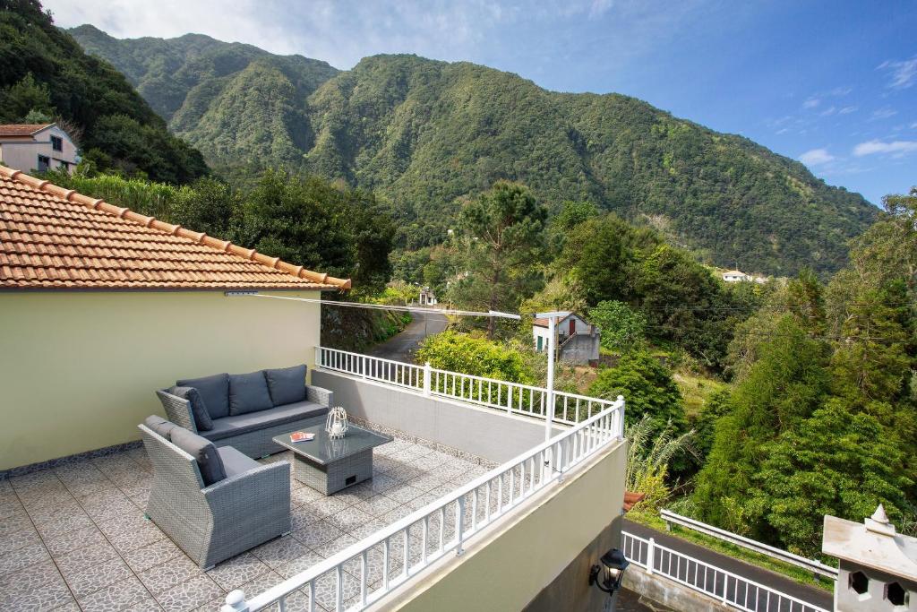 a balcony with a couch and a table and mountains at Casa Estrela Do Norte in Ponta Delgada