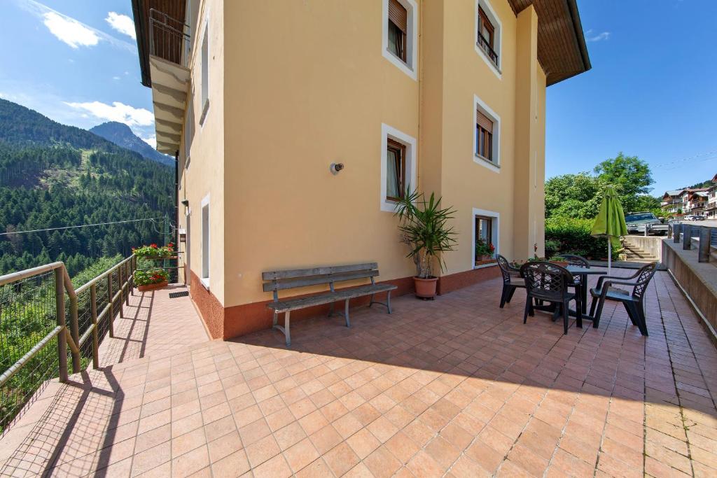 a patio with a bench and tables and chairs at Affittacamere Angelina in San Pietro di Cadore