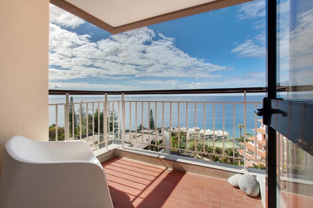 a balcony with a white chair and a view of the ocean at Vista Formosa in Funchal