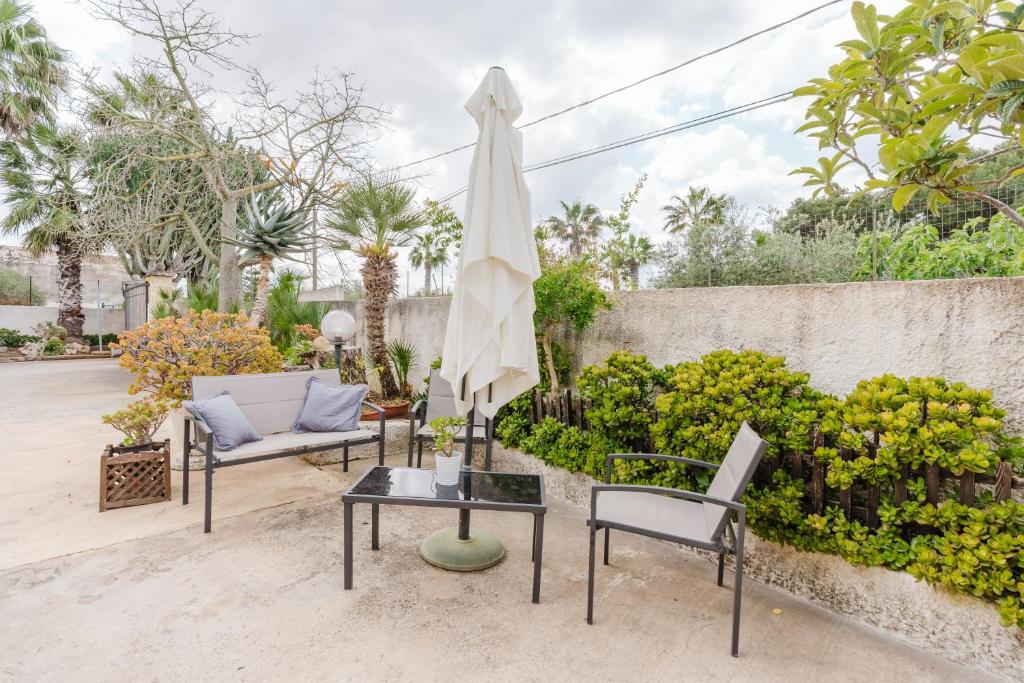 a patio with two chairs and a table with an umbrella at Casa Petros in Marsala