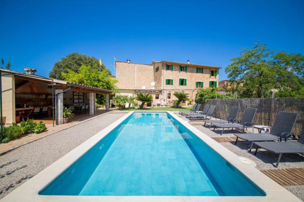 a swimming pool with chairs and a building at Villa Rae in Sóller