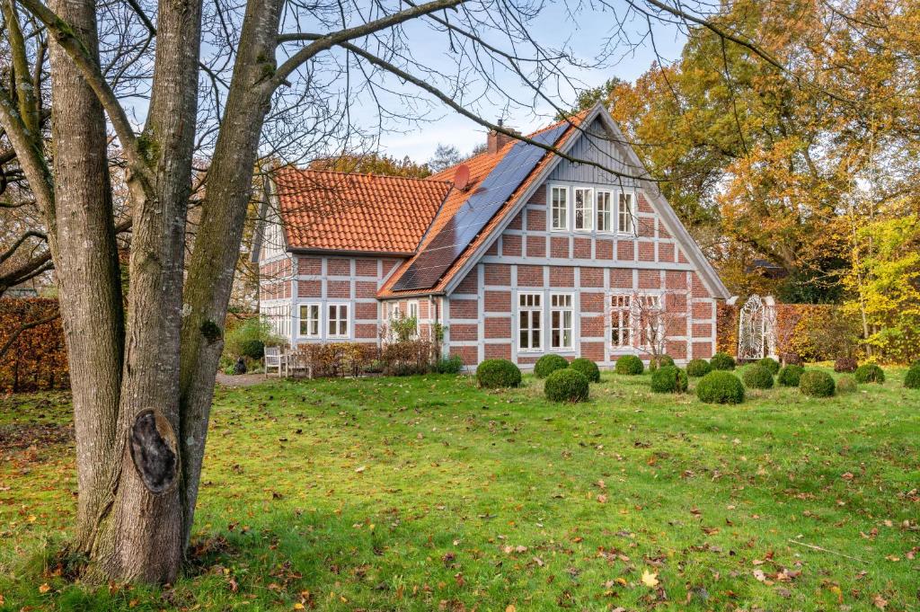 a large red house with a tree in the yard at Landhaus im Garten in Hude