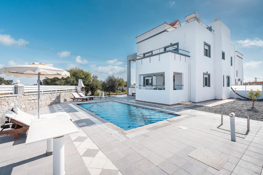 a villa with a swimming pool and a house at White Pearl in Lachania