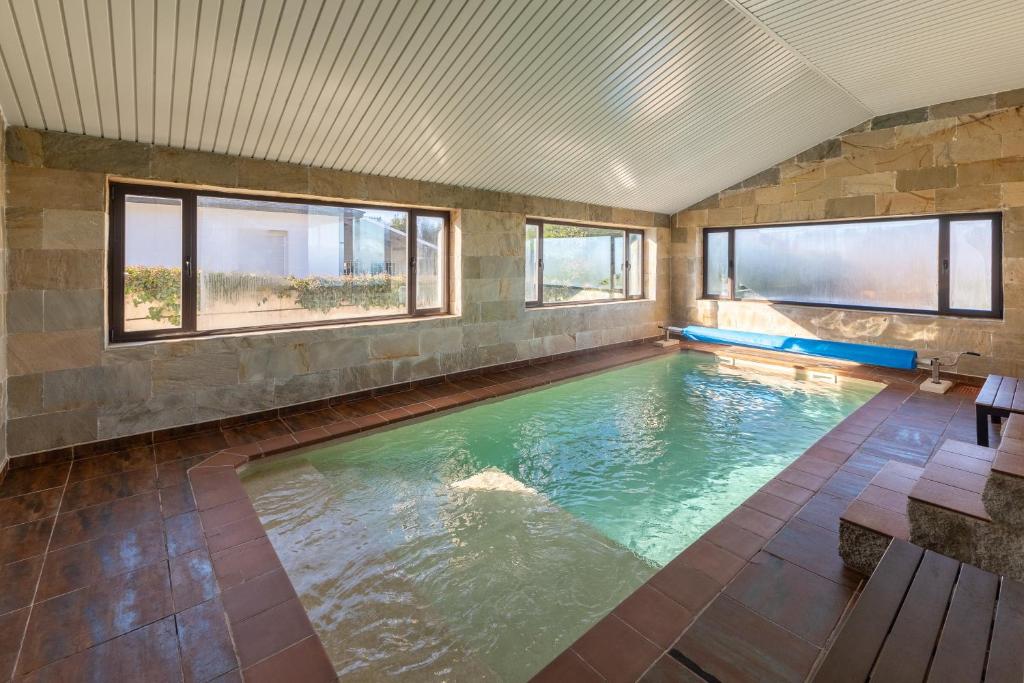 a large indoor swimming pool in a building with windows at El Arrebol Rural in El Espinar