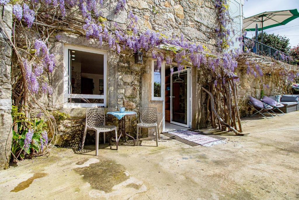 a stone house with wisteria on the side of it at Estúdio Azul in Moledo