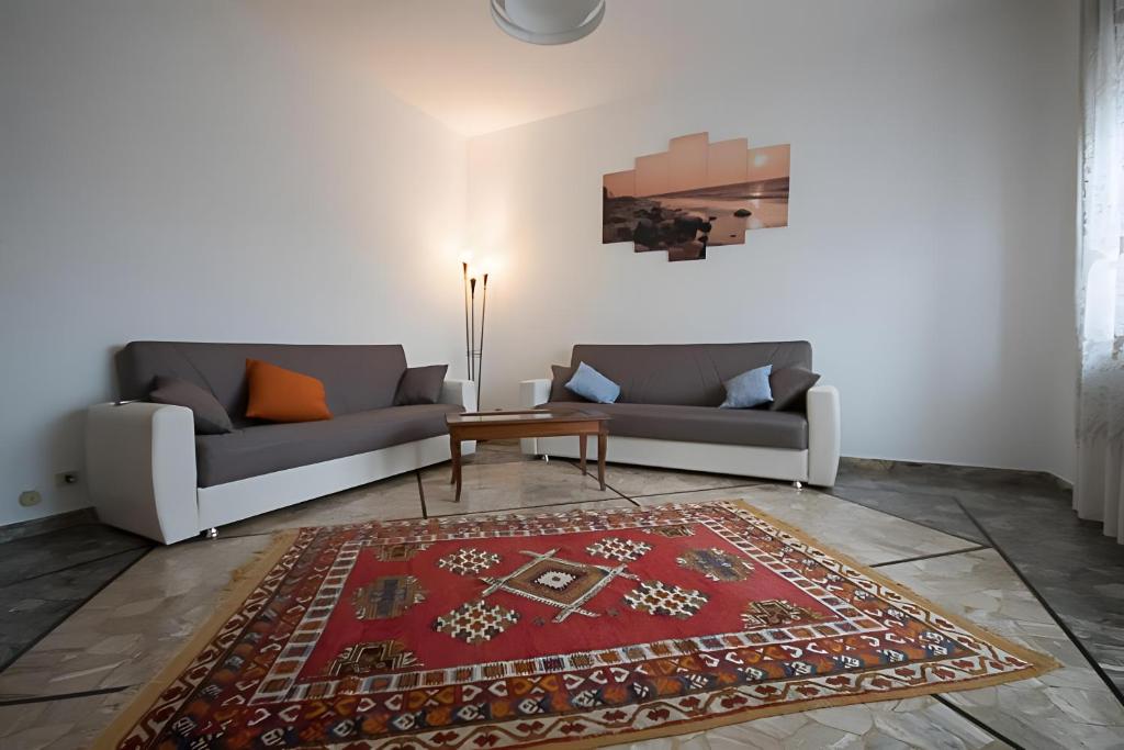 a living room with two couches and a red rug at Serravalle Shopping - Outlet in Serravalle Scrivia