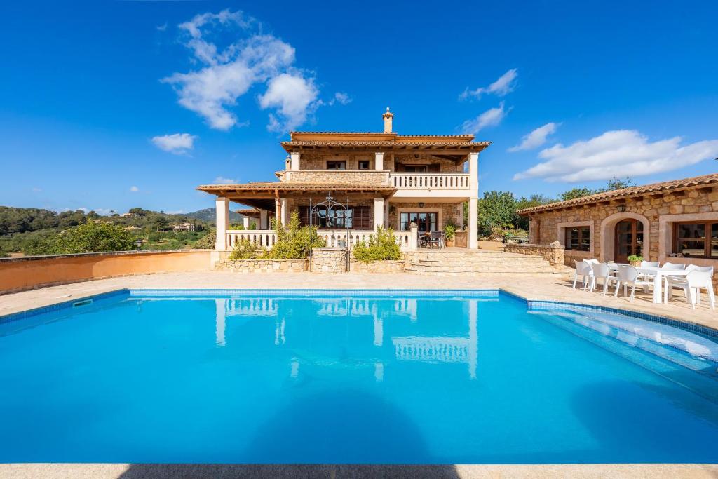 a villa with a swimming pool in front of a house at Turó de na Roca in S'Horta