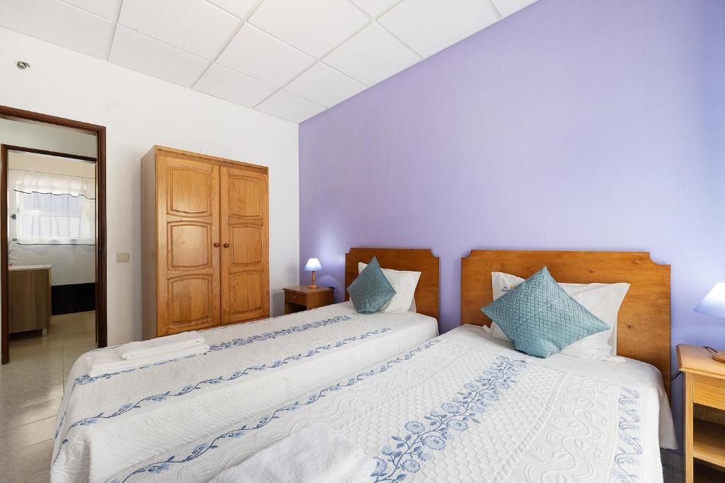a bedroom with two beds and a wooden cabinet at Apartment T2 Malveiro in Odeceixe