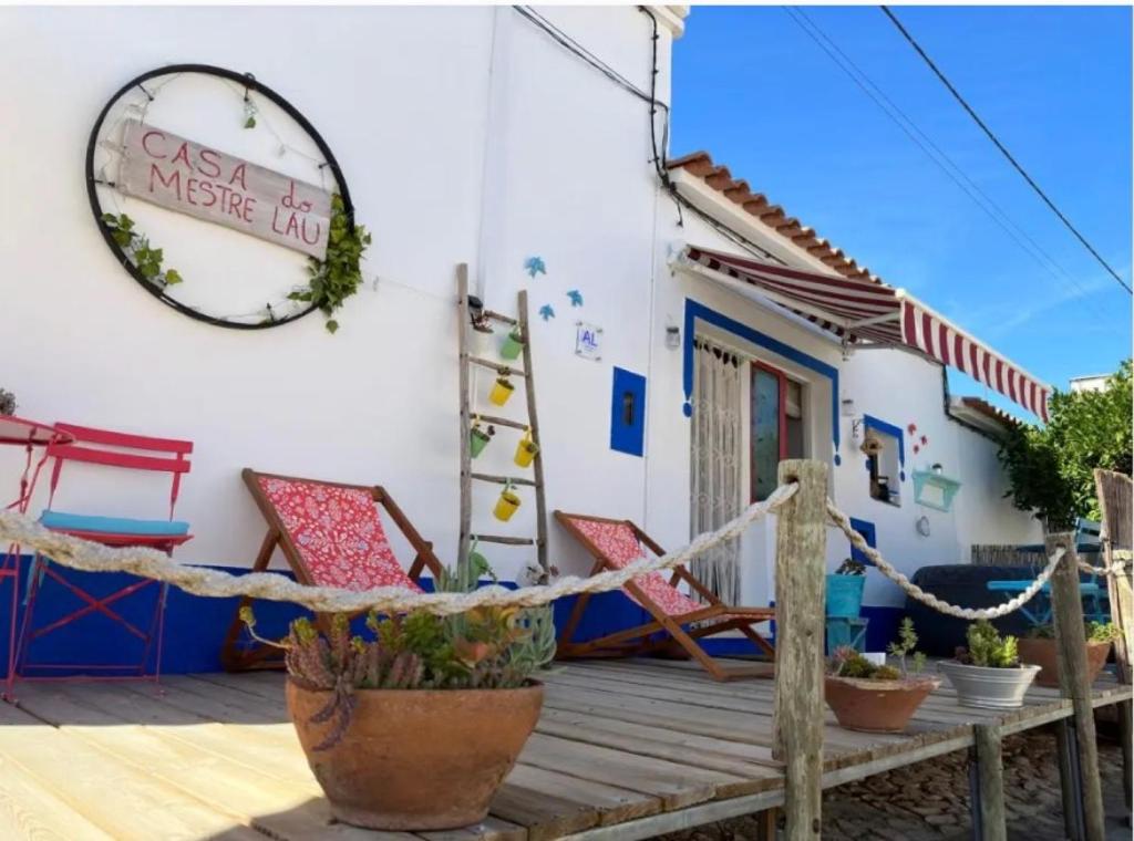 a house with two chairs and a sign on the wall at Casa Do Mestre Lau in Terena