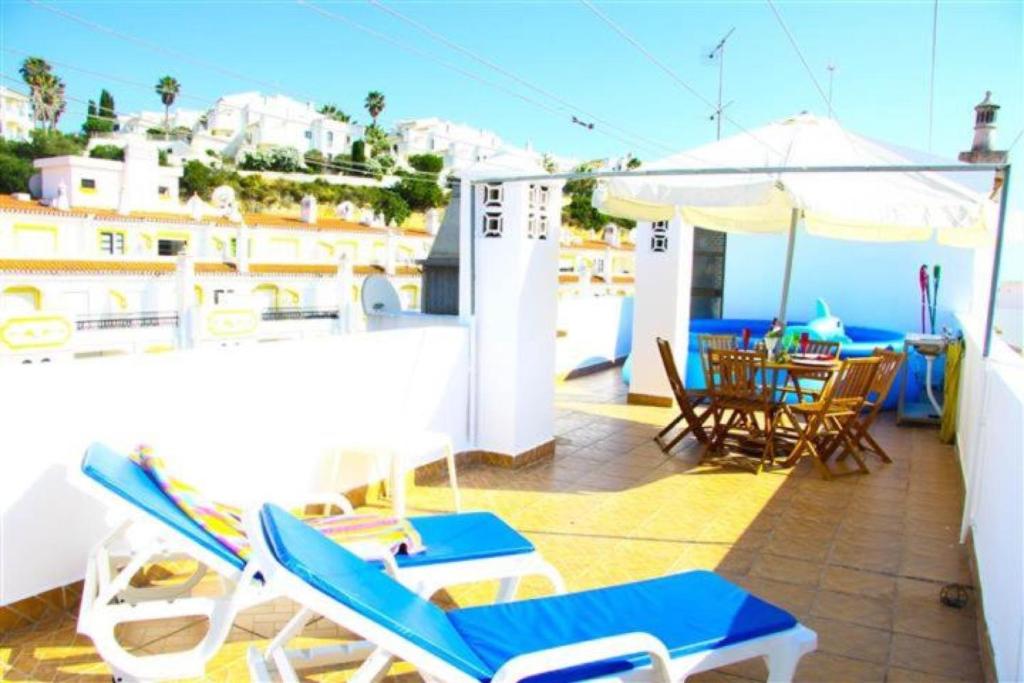 a balcony with chairs and a table and an umbrella at Fernandes Apartment in Carvoeiro