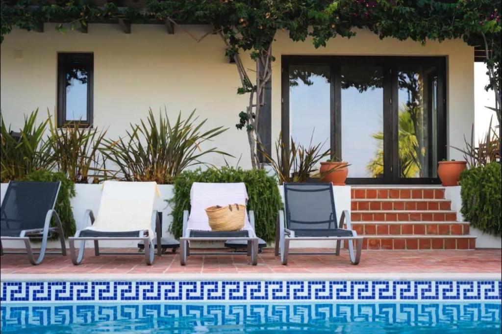 a group of three lawn chairs next to a pool at Villa Laguna - Charmy Villa in Moncarapacho