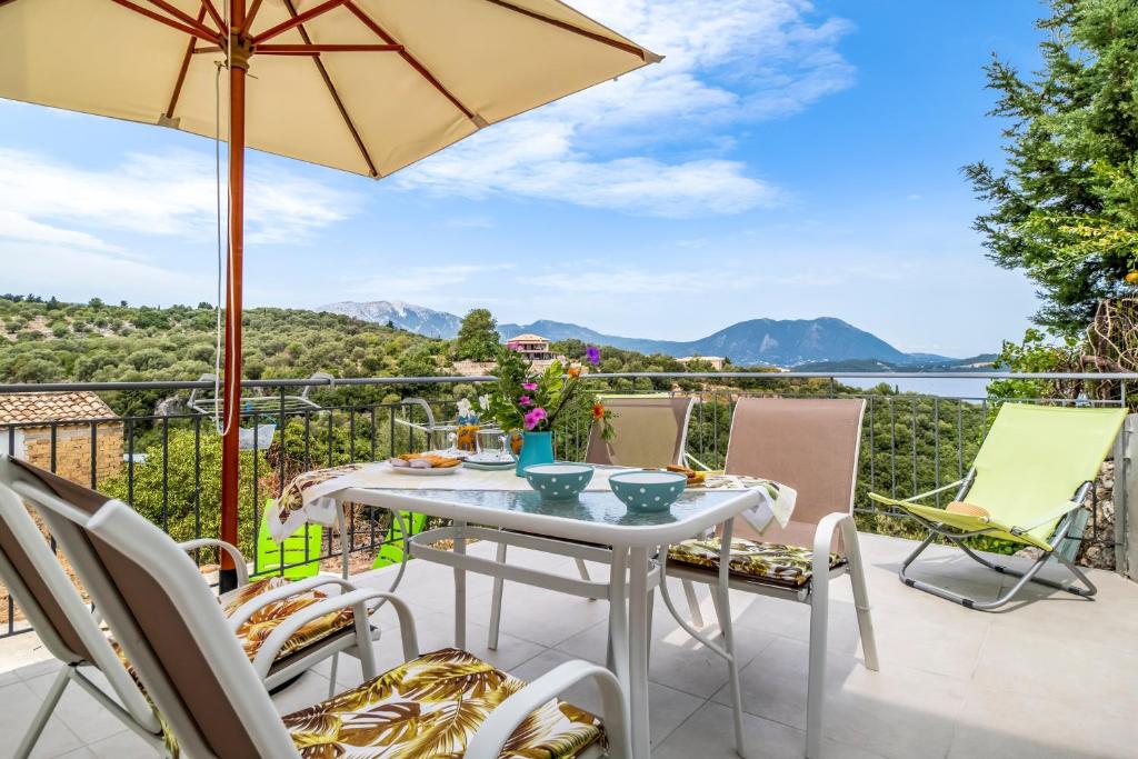 a patio with a table with chairs and an umbrella at Scorpios View Meganisi in Meganisi