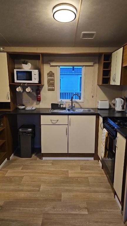a kitchen with a sink and a microwave at Seagulls Sunrise in Seasalter