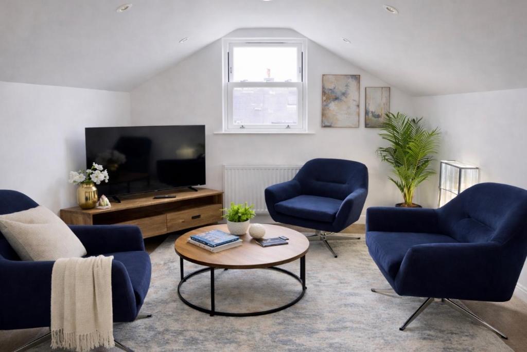 a living room with two blue chairs and a tv at Duplex Apartment - Central Harrogate Apartment in Harrogate
