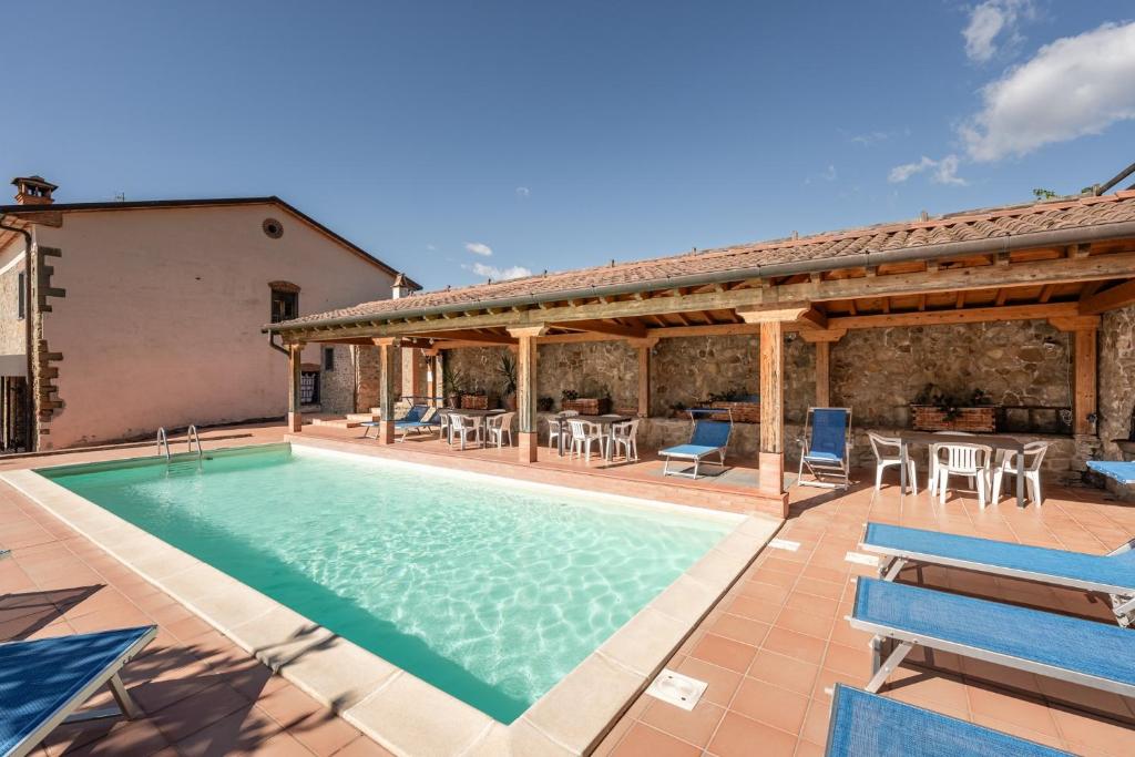 an outdoor swimming pool with a patio and a house at Agriturismo Fadanelli - Le Rondini in Lamporecchio