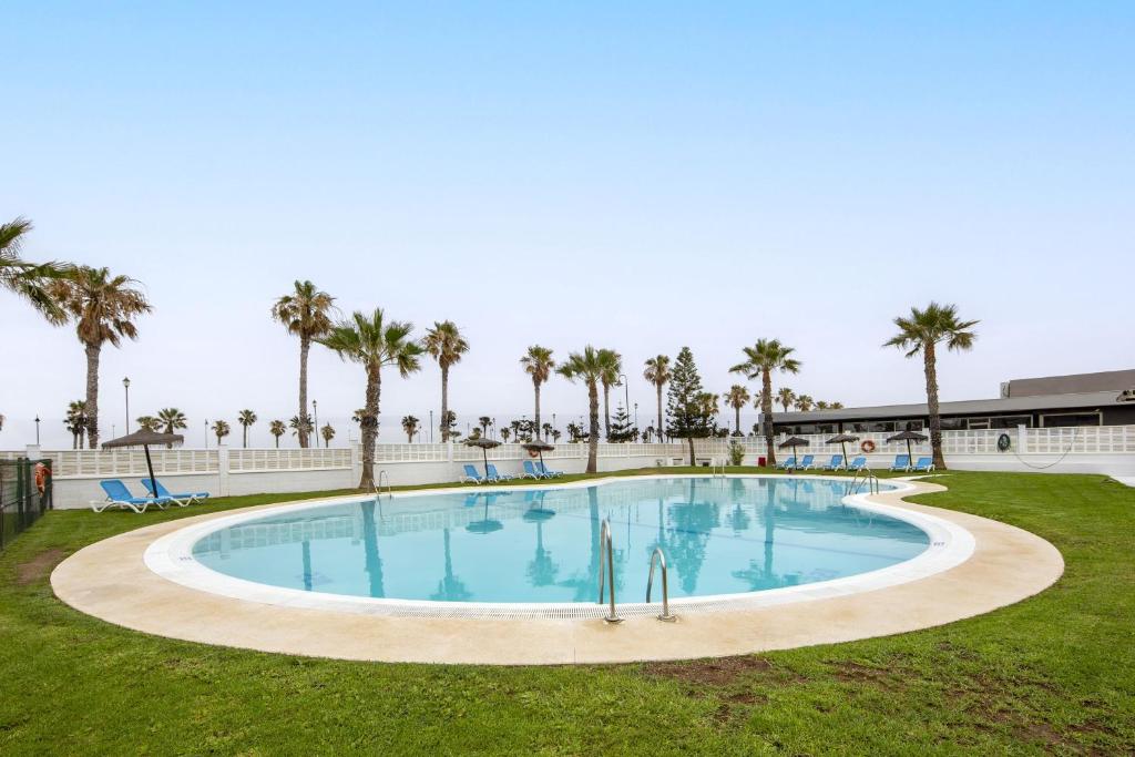 a large pool with palm trees in the background at Sofie apartamento turístico in Roquetas de Mar