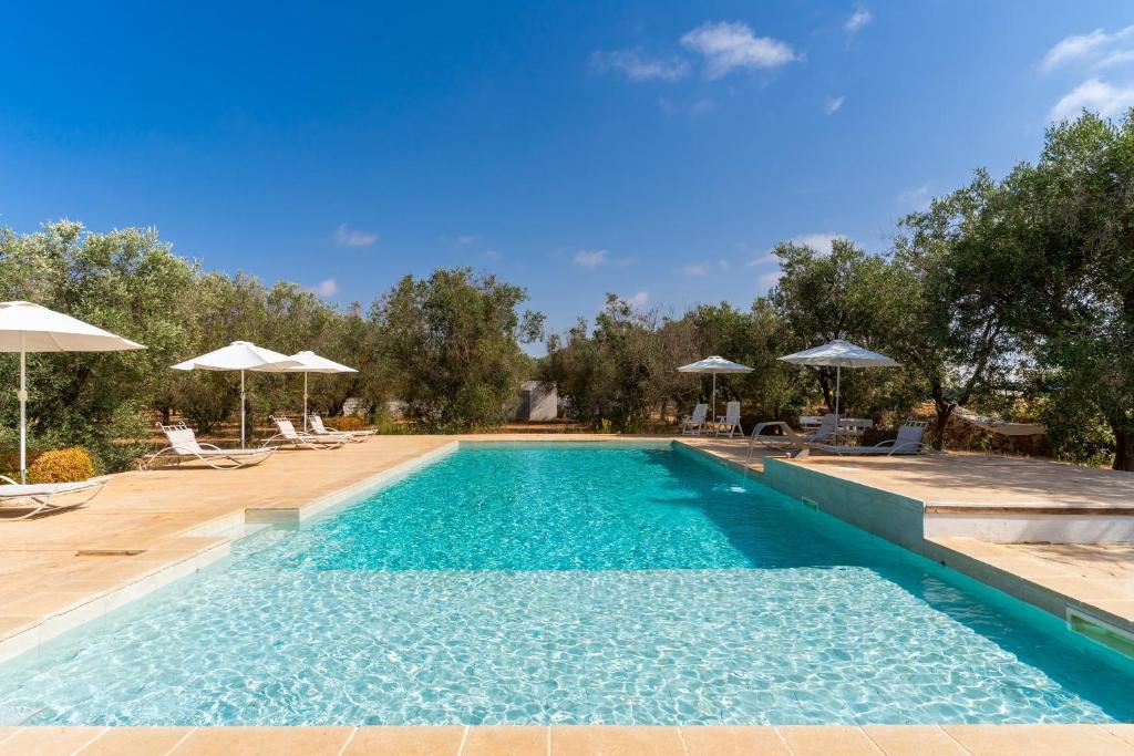 a swimming pool with chairs and umbrellas at Domus mea salento Arazzo Verde in Ugento