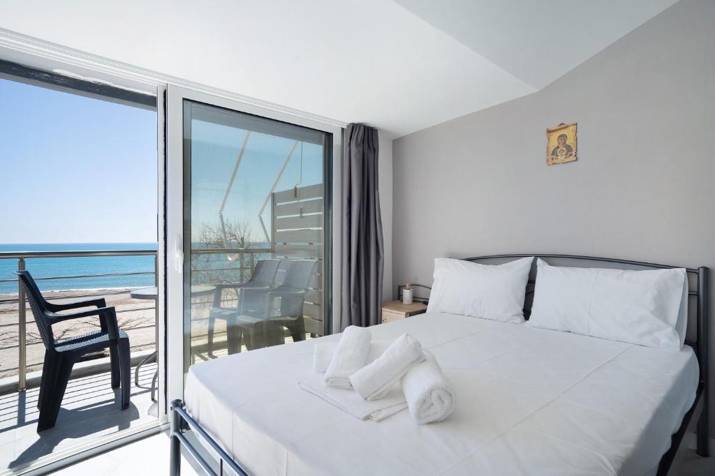 a bedroom with a white bed and a balcony at Iguana studio 17 in Preveza
