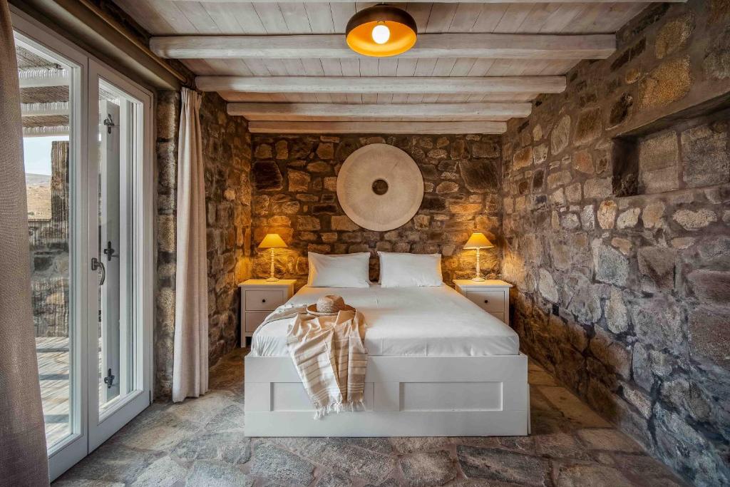 a bedroom with a bed and a stone wall at Villa Vagia in Vayiá