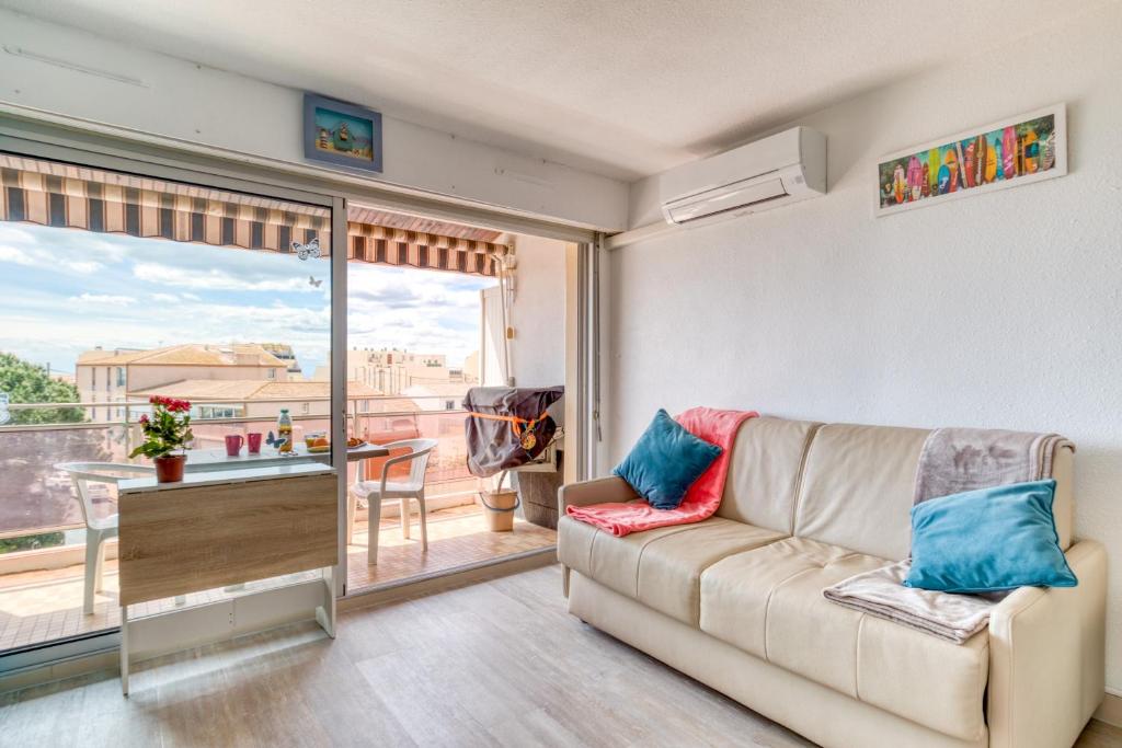 a living room with a couch and a balcony at Les Ptits Loups, le Grau d'Agde in Le Grau-dʼAgde