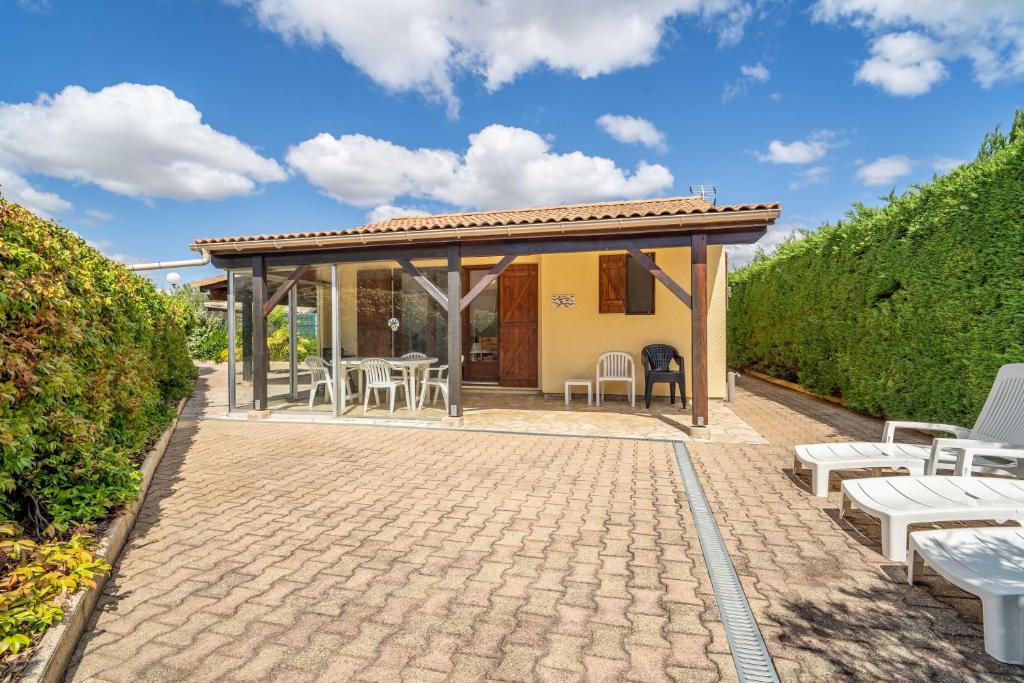 a patio with tables and chairs and a pavilion at Maison 6 Pers, proche de la plage in Vendres