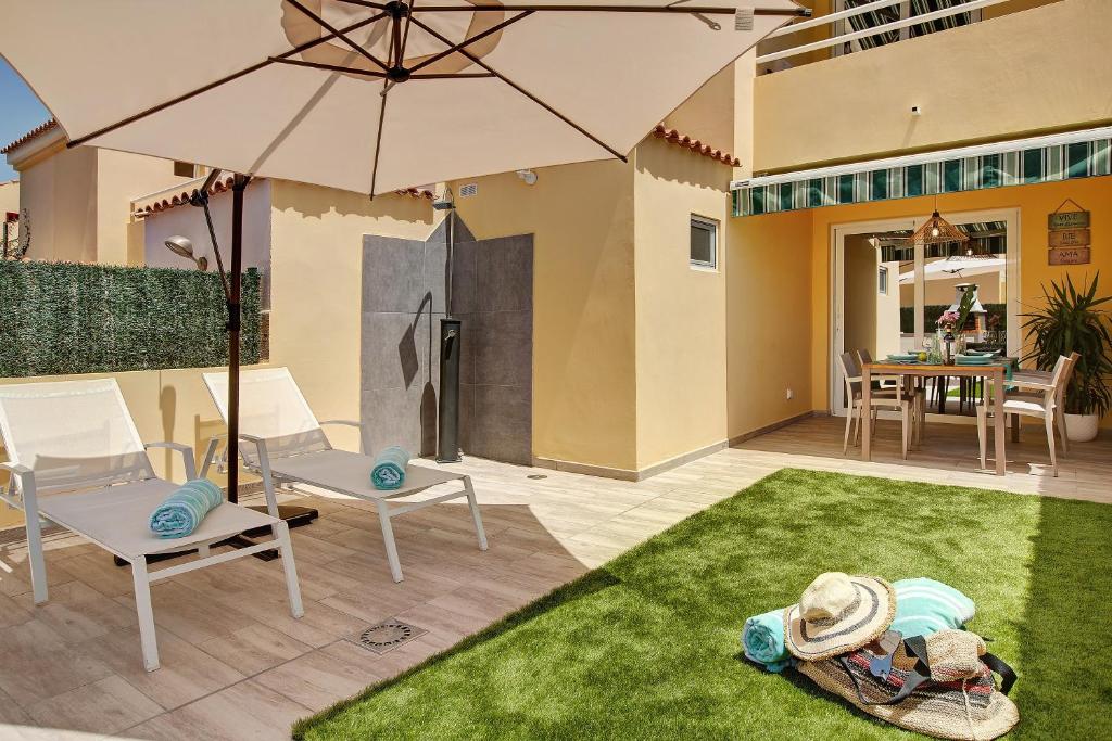 a patio with an umbrella and chairs and a table at Bungalow Sonemar Sunshine in Maspalomas
