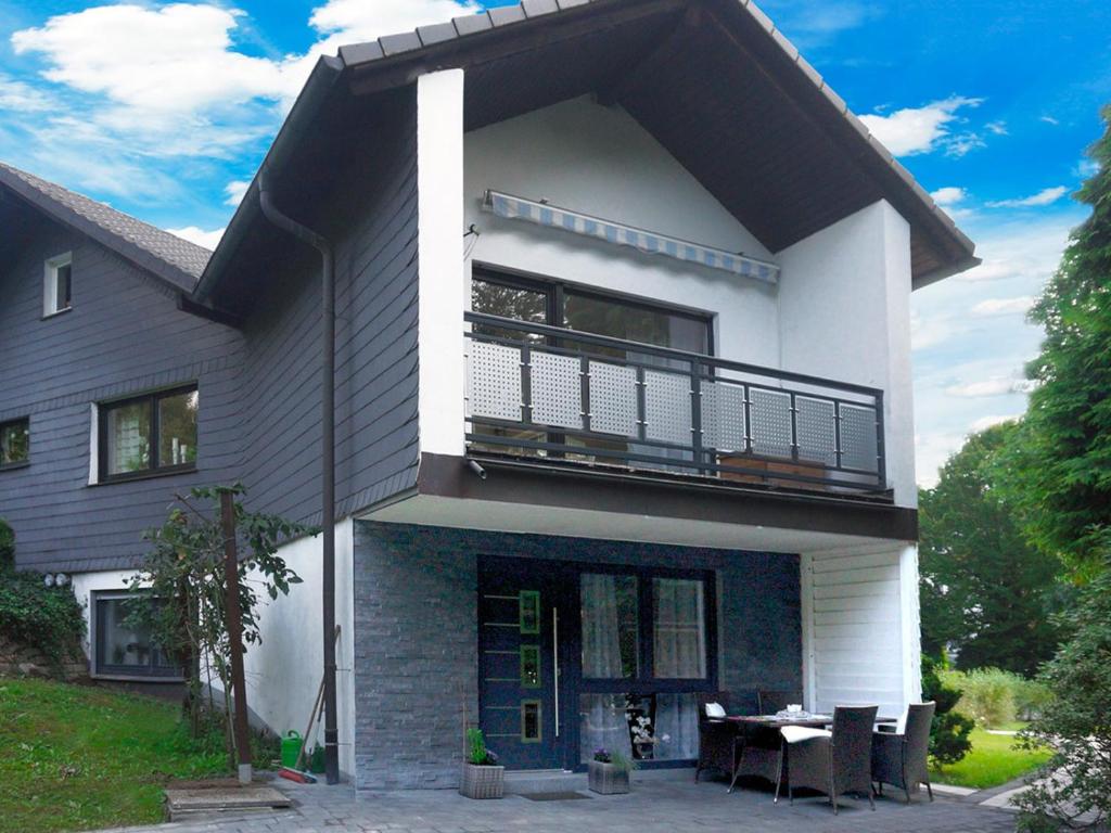 a white house with a balcony and a table at Fewo Meisennest, 50 Qm in Saalhausen