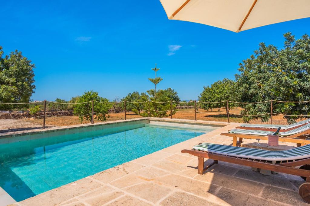 a swimming pool with two chairs and an umbrella at Son Sunyer in La Aranjasa