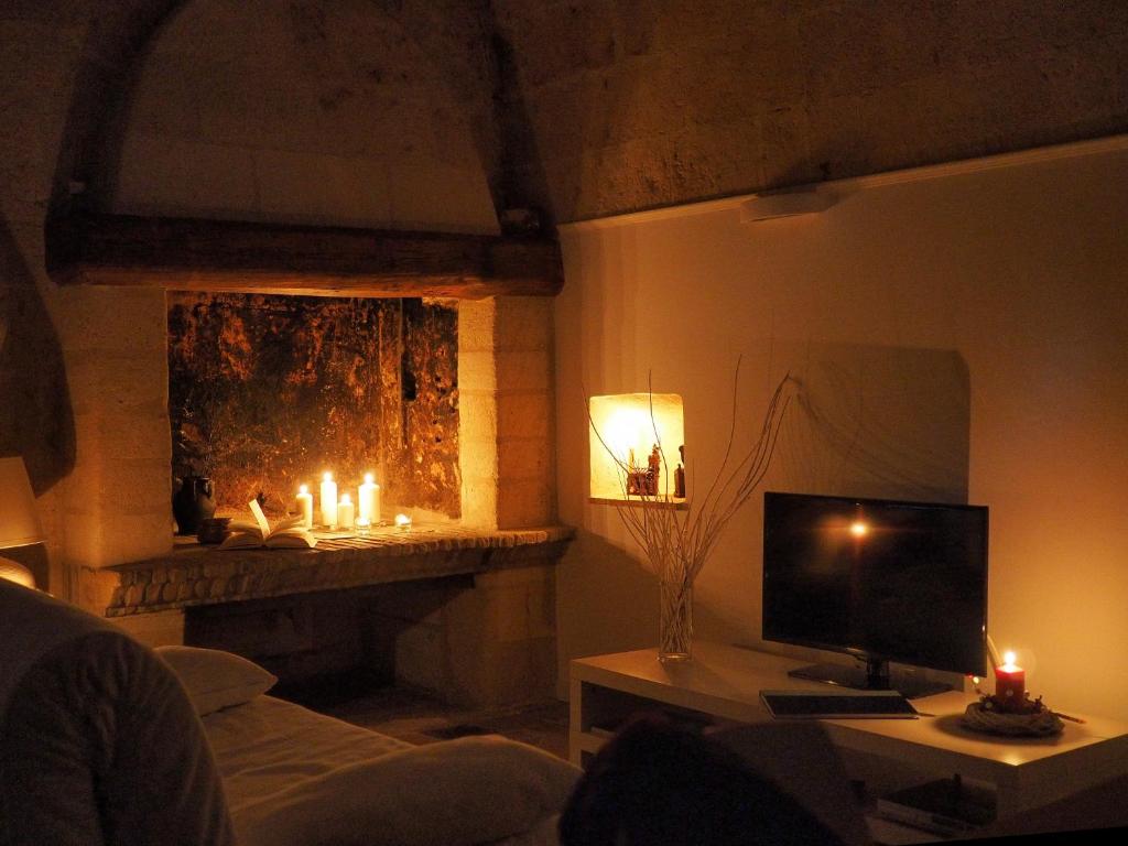 un salon avec une cheminée, une télévision et des bougies dans l'établissement Ai Sassi di Pietro, à Matera