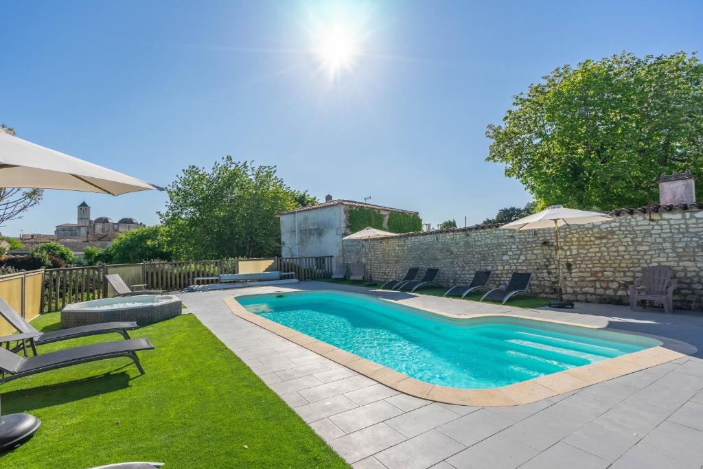 a swimming pool in a yard with chairs and an umbrella at Les gîtes du logis in Saint-Romain-de-Benet