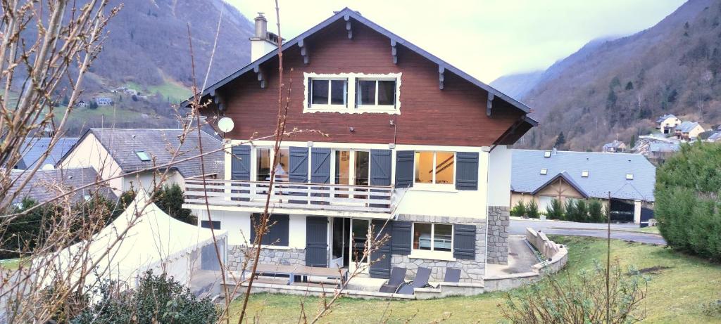 a house on a hill with mountains in the background at Sublime Chalet 14 Pers Spa Extrieur in Cauterets