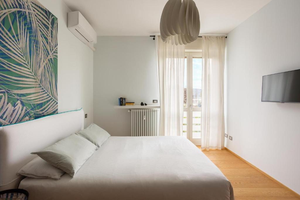 a white bedroom with a bed and a tv at Suite 51 - Arona in Arona