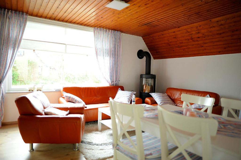 a living room with orange furniture and a table at Ferienhaus Friedrichskoog - Spitze in Friedrichskoog-Spitze