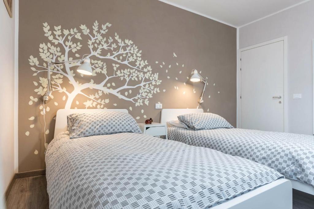 a bedroom with two beds and a tree mural on the wall at Appartamento Le Quattro Stagioni in Levico Terme