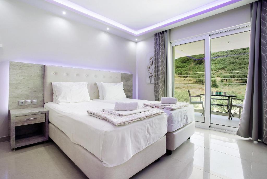 a white bedroom with a large bed and a balcony at Villa Dionysia Studio S6 in Alikanas