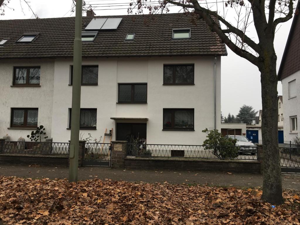 ein weißes Haus mit schwarzen Fenstern und einem Baum in der Unterkunft Gästehaus Windheim (Karlsruhe-Knielingen) in Karlsruhe