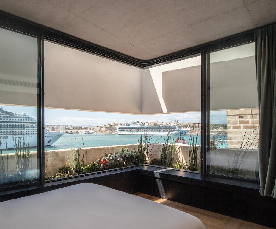 a bedroom with large windows with a view of a ship at Stilla, San Mikiel in Senglea