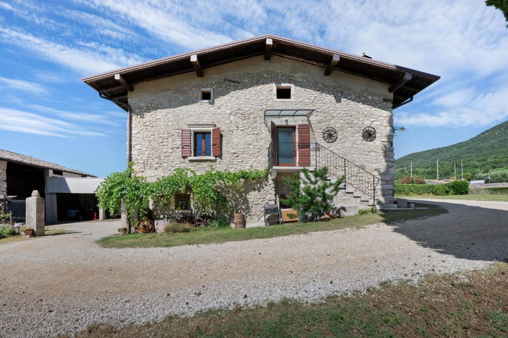 an old stone house with red windows on a road at Casa Loppia 2022 in Caprino Veronese