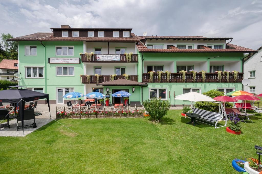 a large building with tables and umbrellas in a yard at Gruppenferienhaus Dressel in Warmensteinach