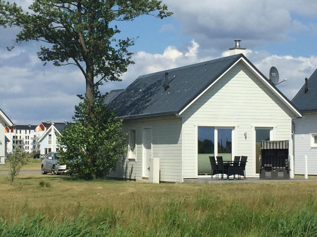 a white house with a table and chairs in front of it at Skipper Hus by Seeblick Ferien in Olpenitz