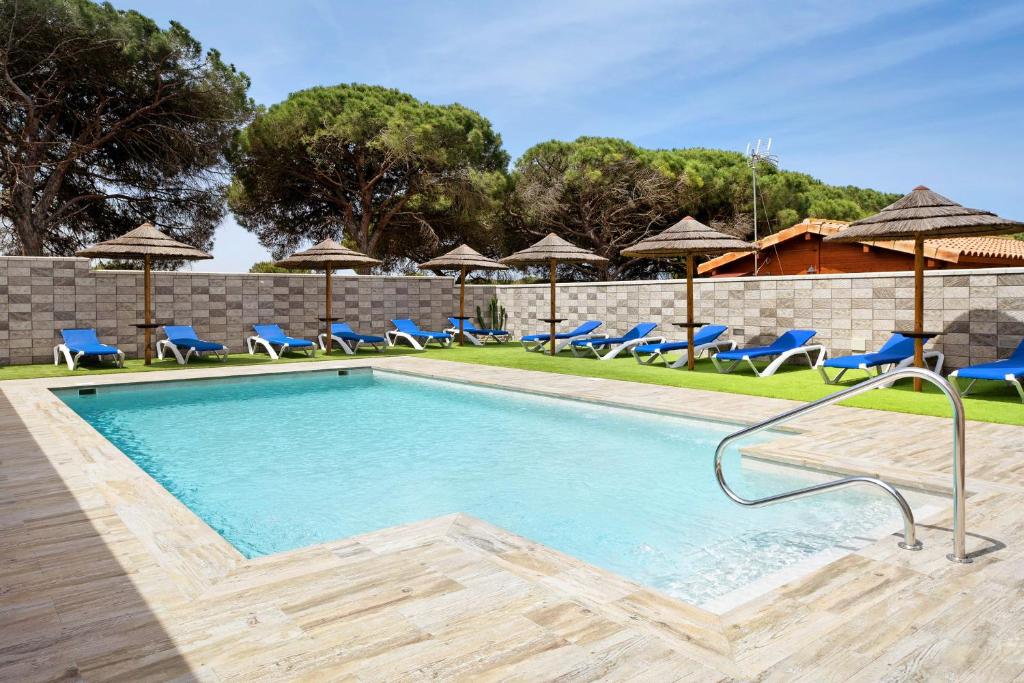 a swimming pool with blue chairs and umbrellas at Casa Torre De Meca 2 Shared Pool in Los Caños de Meca