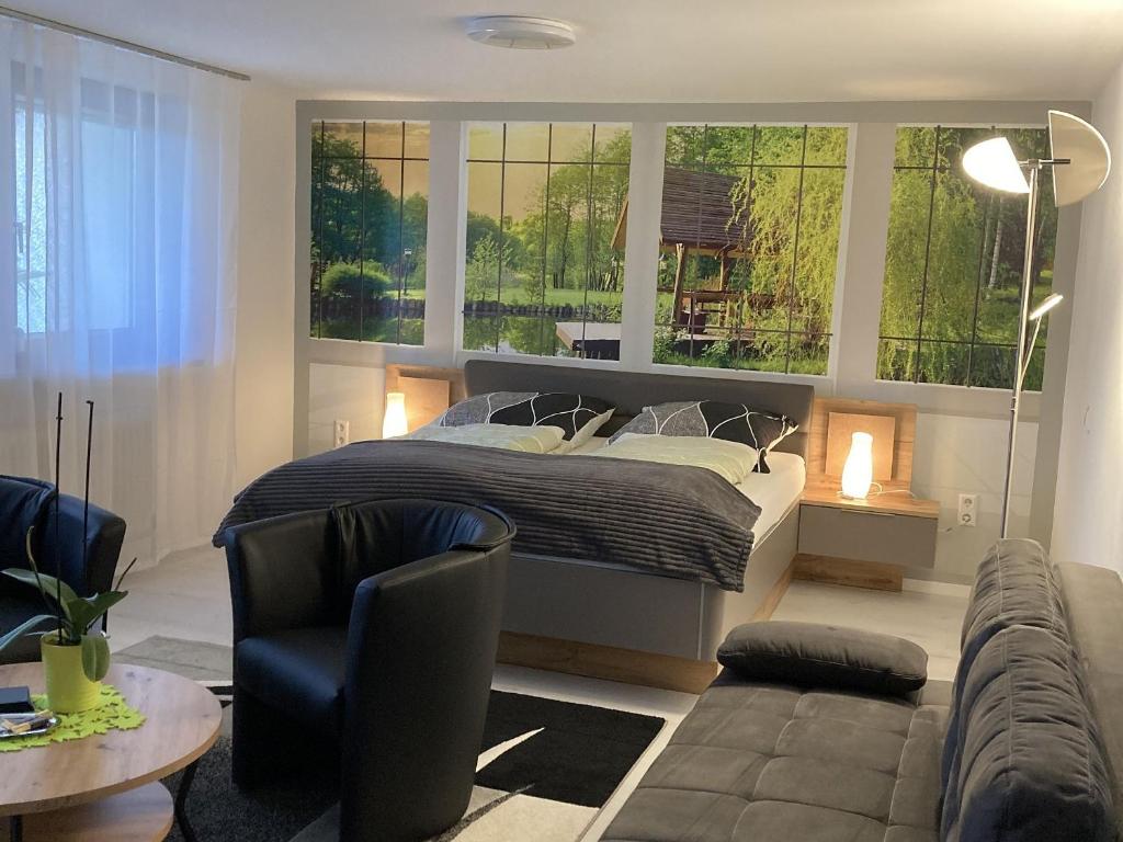 a bedroom with a bed and a couch and windows at Ferienwohnung Palmengarten in Lichtenstein