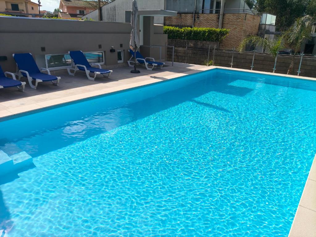 a large blue swimming pool with blue chairs on a patio at Maia House da Piscina in Folgosa