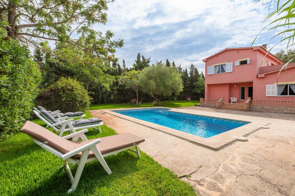 a backyard with a swimming pool and a pink house at Luna Azul in Sant Jordi